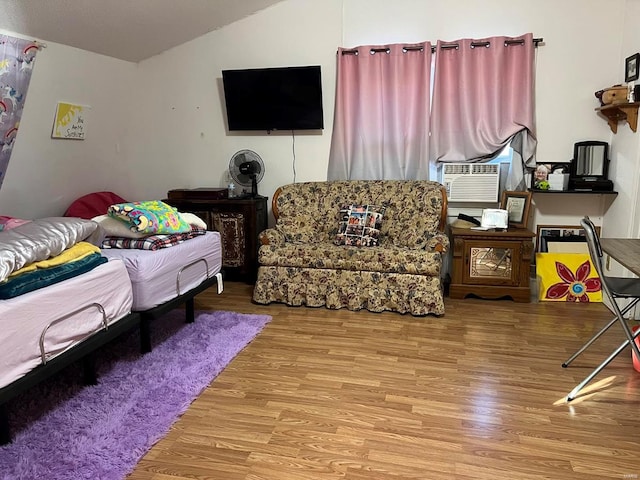 bedroom featuring lofted ceiling, cooling unit, and light wood-type flooring