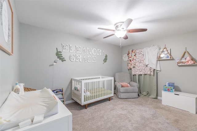 bedroom with a crib, light carpet, and ceiling fan