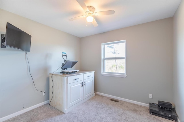 unfurnished office featuring ceiling fan and light carpet