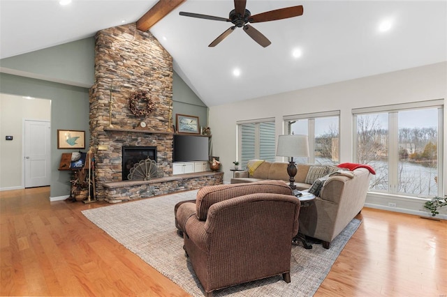 living area with light wood finished floors, baseboards, a stone fireplace, high vaulted ceiling, and beam ceiling