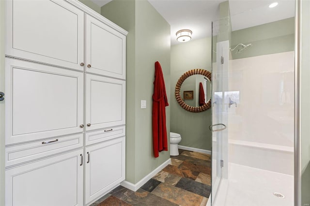 full bath featuring toilet, baseboards, walk in shower, and stone tile flooring