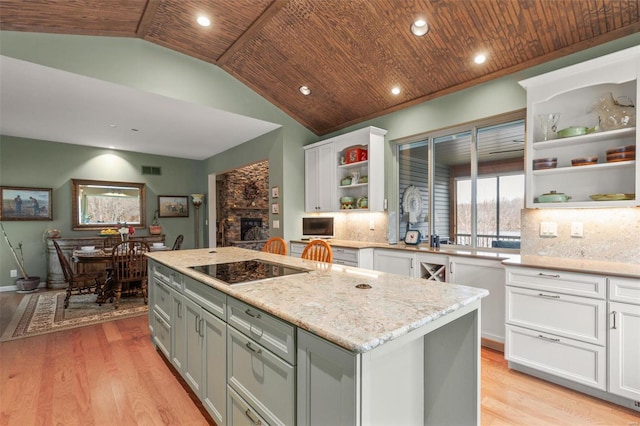 kitchen featuring light wood finished floors, wooden ceiling, black electric cooktop, white cabinetry, and open shelves