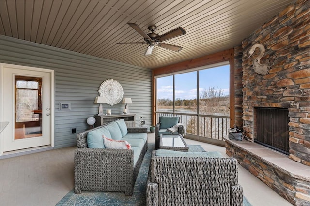 sunroom featuring ceiling fan and an outdoor stone fireplace