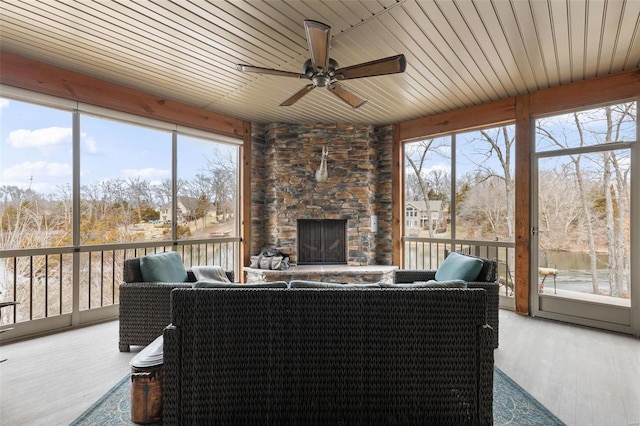 sunroom / solarium featuring ceiling fan, a fireplace, and wooden ceiling