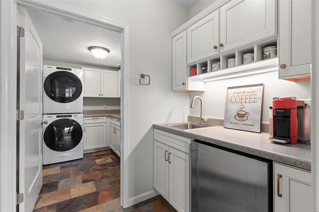 laundry room with stacked washer and dryer, stone finish flooring, cabinet space, and a sink