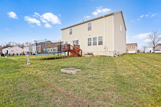 back of property featuring a yard and a trampoline