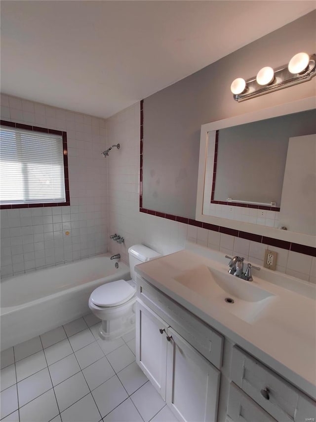 full bathroom with vanity, tile patterned floors, tiled shower / bath, toilet, and tile walls