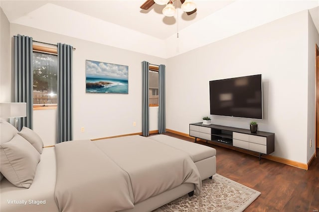 bedroom featuring ceiling fan, dark wood-type flooring, and a tray ceiling