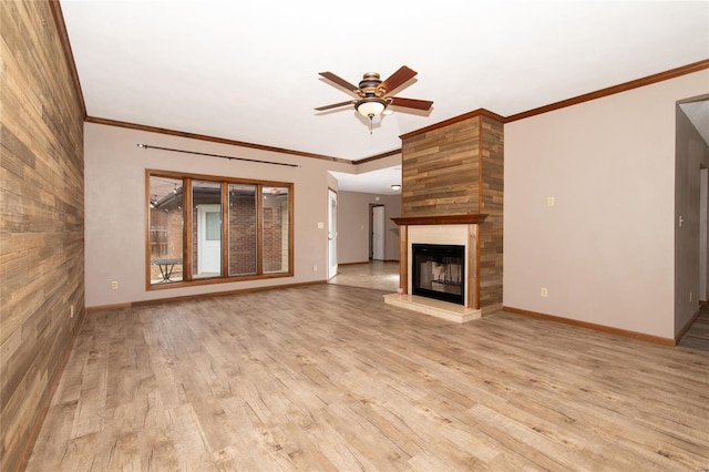 unfurnished living room with light wood-type flooring, a large fireplace, ceiling fan, and crown molding