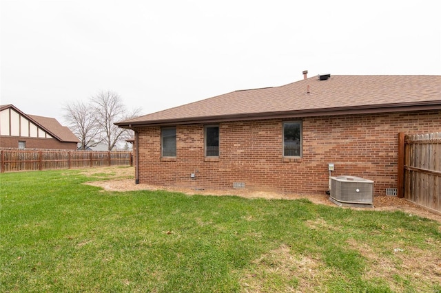 back of property featuring central air condition unit and a yard