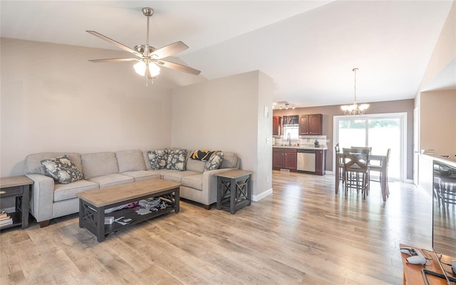 living room featuring ceiling fan with notable chandelier, light wood-type flooring, vaulted ceiling, and sink