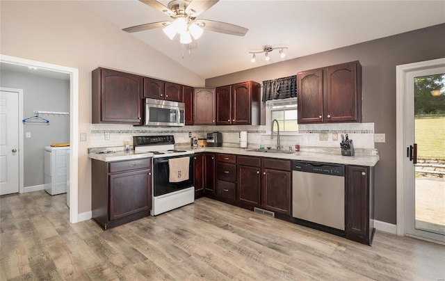 kitchen with lofted ceiling, sink, decorative backsplash, light wood-type flooring, and appliances with stainless steel finishes