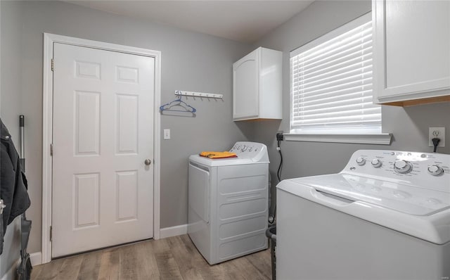 washroom with washing machine and clothes dryer, light hardwood / wood-style flooring, and cabinets