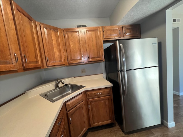 kitchen featuring stainless steel fridge, a textured ceiling, and sink