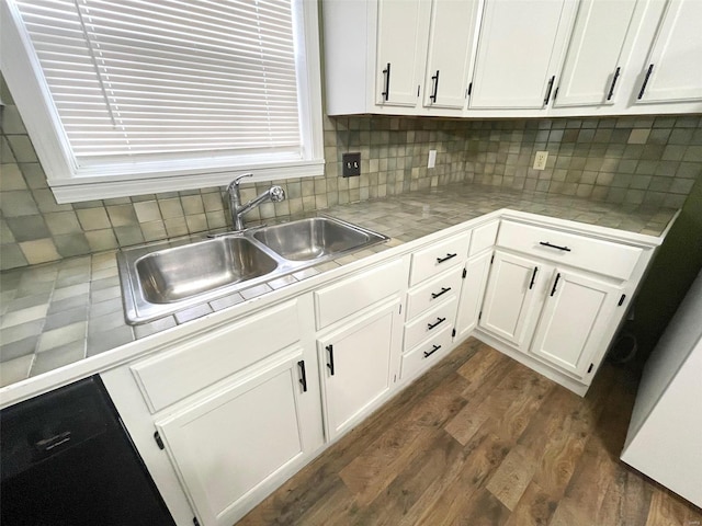 kitchen with dark wood-type flooring, white cabinets, sink, tasteful backsplash, and tile counters