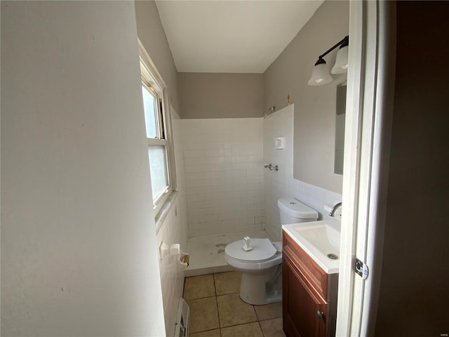 bathroom with vanity, tile patterned floors, toilet, tile walls, and a tile shower