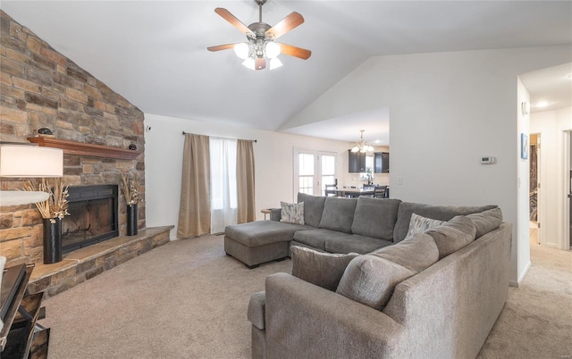 carpeted living room featuring lofted ceiling, ceiling fan with notable chandelier, and a stone fireplace