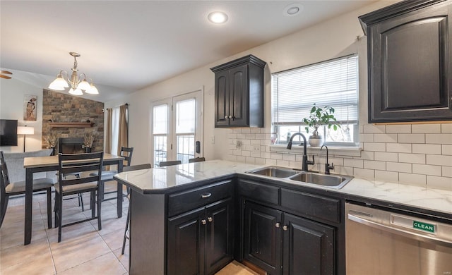 kitchen featuring kitchen peninsula, stainless steel dishwasher, lofted ceiling, backsplash, and sink