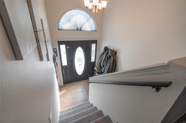 tiled entrance foyer featuring a high ceiling and a notable chandelier