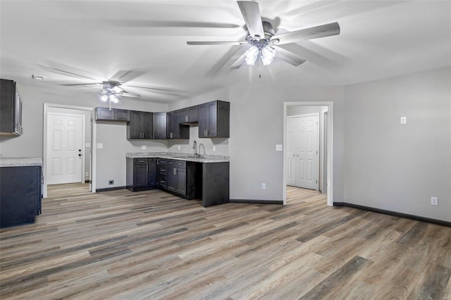 kitchen with ceiling fan, light hardwood / wood-style floors, dark brown cabinetry, and sink