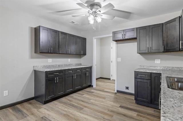 kitchen featuring light stone countertops, light hardwood / wood-style flooring, and ceiling fan