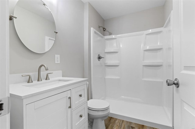 bathroom featuring toilet, vanity, wood-type flooring, and walk in shower