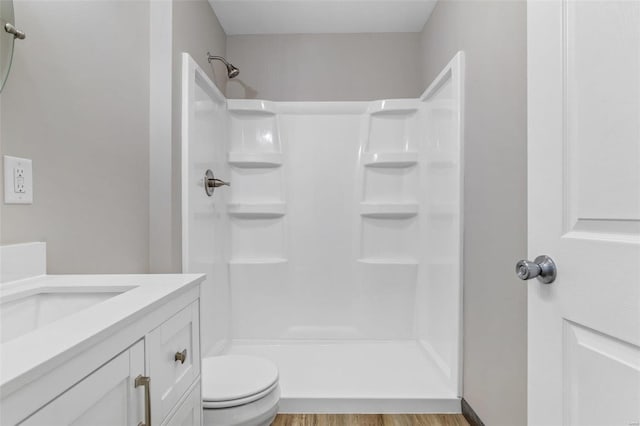 bathroom featuring walk in shower, toilet, vanity, and hardwood / wood-style flooring