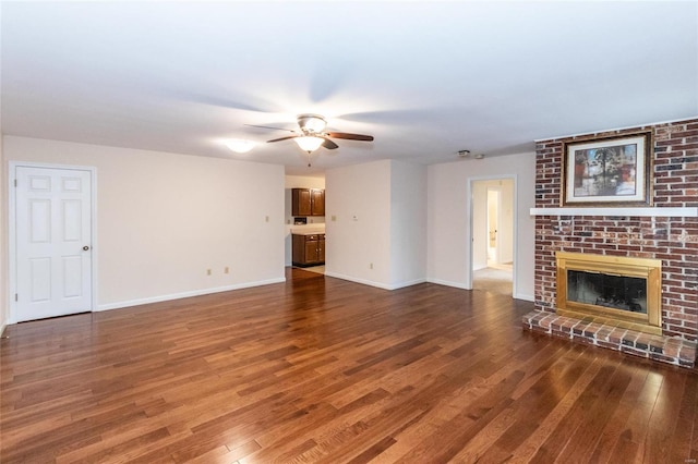 unfurnished living room with ceiling fan, dark hardwood / wood-style flooring, and a brick fireplace