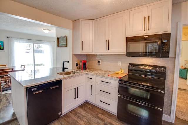 kitchen with black appliances, white cabinetry, kitchen peninsula, and sink