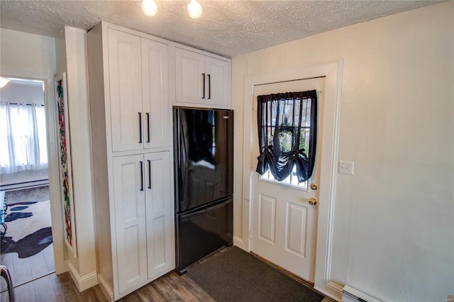 entryway featuring a textured ceiling, plenty of natural light, dark wood-type flooring, and a baseboard radiator