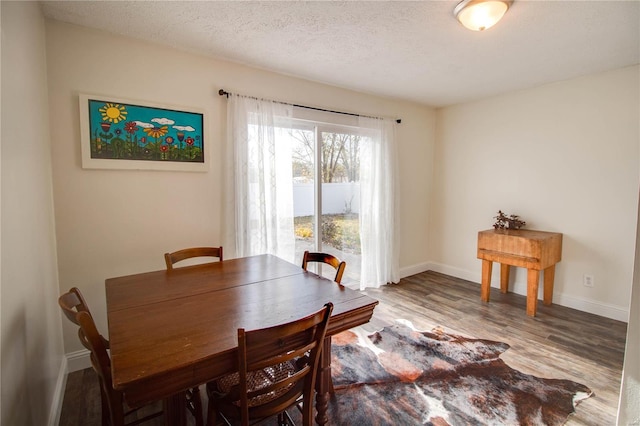 dining room featuring wood-type flooring and a textured ceiling