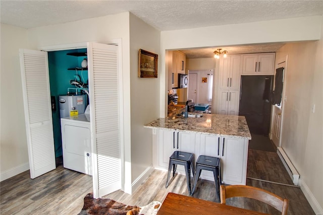 kitchen featuring kitchen peninsula, electric water heater, a textured ceiling, washer / dryer, and white cabinetry