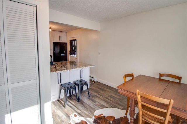 dining space with wood-type flooring and a textured ceiling