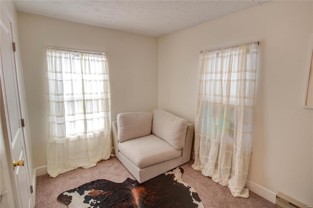 sitting room with carpet floors, a textured ceiling, and a baseboard heating unit