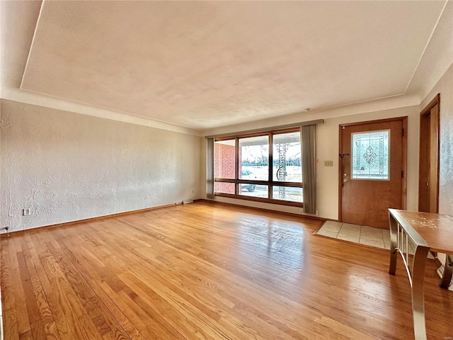 unfurnished living room with light wood-style flooring and a textured wall