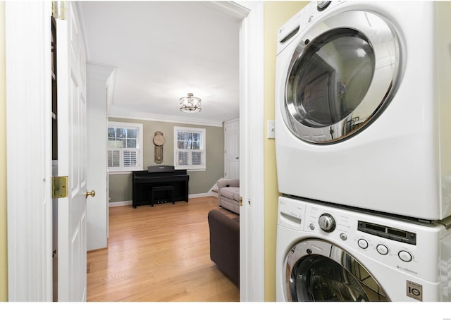 laundry room with laundry area, baseboards, stacked washer / dryer, ornamental molding, and light wood-style floors