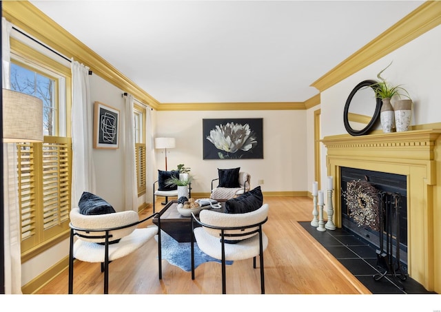 living area featuring a fireplace with flush hearth, ornamental molding, wood finished floors, and baseboards