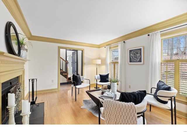 living room with light wood-style floors, a fireplace with flush hearth, stairway, and crown molding