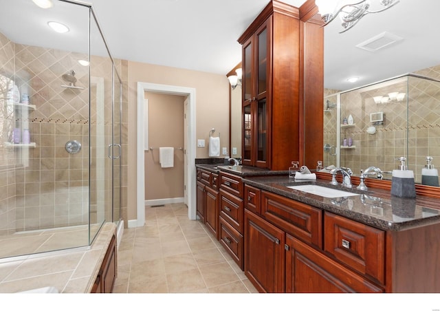 bathroom featuring double vanity, a stall shower, a sink, and tile patterned floors