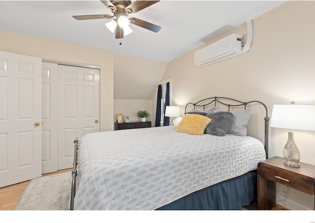 bedroom featuring wood finished floors, a ceiling fan, vaulted ceiling, a wall mounted AC, and a closet