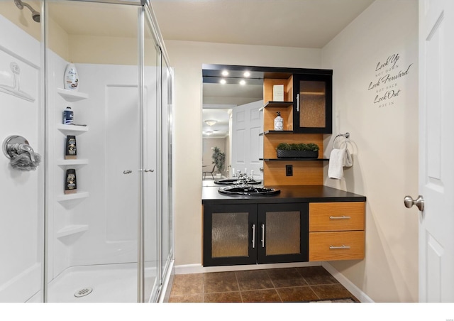 bathroom with a stall shower, tile patterned flooring, vanity, and baseboards