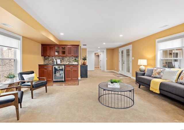 living room with a dry bar, beverage cooler, visible vents, light colored carpet, and french doors