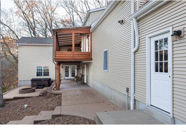 entrance to property featuring french doors, a hot tub, a patio, and a balcony