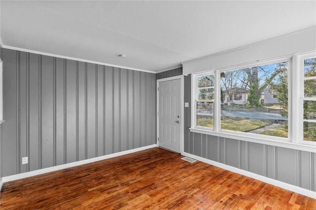 unfurnished room featuring hardwood / wood-style floors, plenty of natural light, and ornamental molding