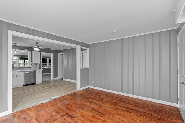 unfurnished living room featuring ceiling fan, light hardwood / wood-style flooring, sink, and ornamental molding