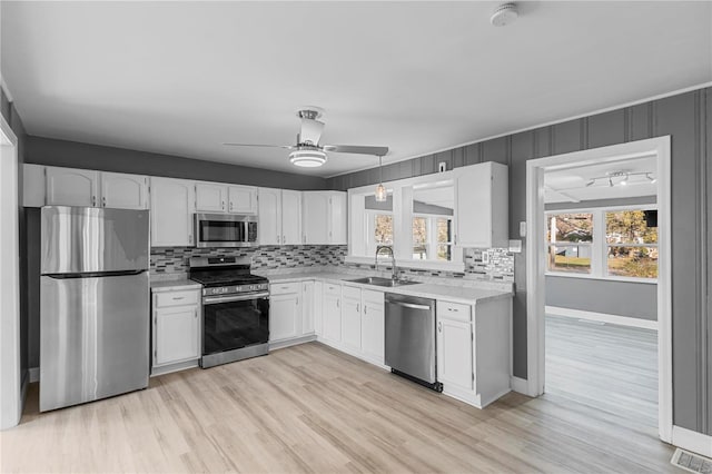 kitchen featuring backsplash, sink, ceiling fan, appliances with stainless steel finishes, and white cabinetry