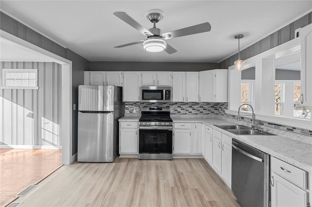 kitchen with sink, light hardwood / wood-style flooring, decorative backsplash, appliances with stainless steel finishes, and white cabinetry