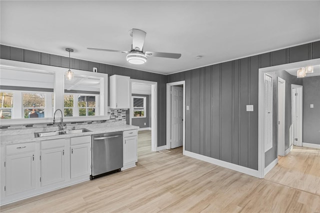 kitchen featuring sink, light hardwood / wood-style flooring, stainless steel dishwasher, backsplash, and white cabinets