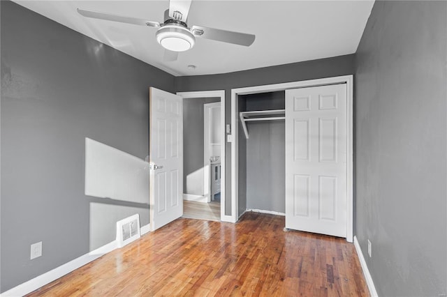 unfurnished bedroom featuring ceiling fan, wood-type flooring, and a closet