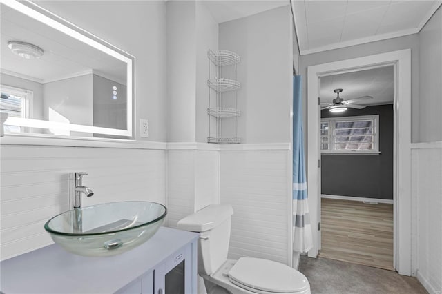 bathroom featuring ceiling fan, crown molding, hardwood / wood-style floors, toilet, and wooden walls